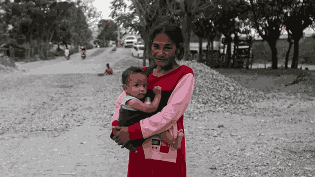 Di jalur lingkar tambang bebatuan di Kelurahan Buluri, Palu, Sulawesi Tengah, pada Sabtu 25 Mei 2024, seorang ibu menggendong anaknya tanpa menggunakan alat pelindung mulut dan hidung. Gambar oleh BBC Indonesia