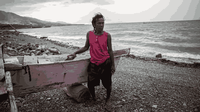 Yongga, seorang nelayan Buluri, berdiri di dekat perahunya yang diparkir di pantai Kelurahan Buluri di Palu, Sulawesi Tengah, pada Sabtu 25 Mei 2024. Gambar olehh BBC Indonesia